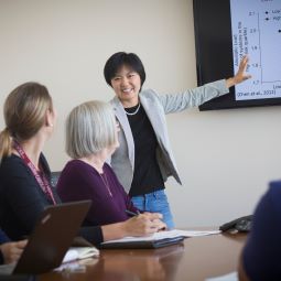 Person presenting information on a TV screen during a meeting