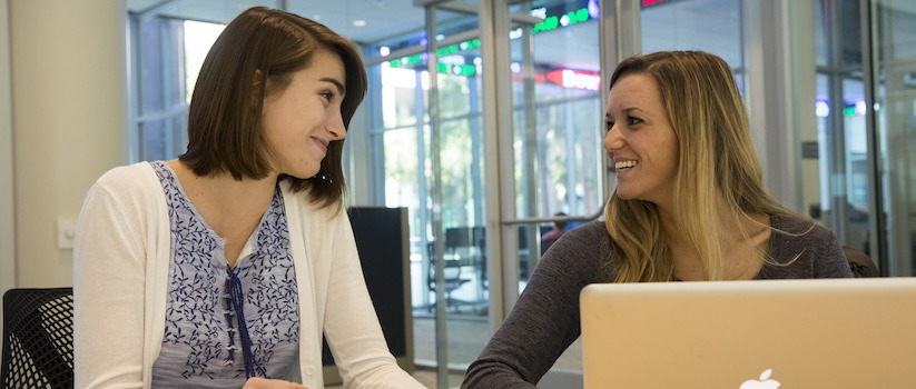 Two people in front of a computer and paper working together in a small conference room