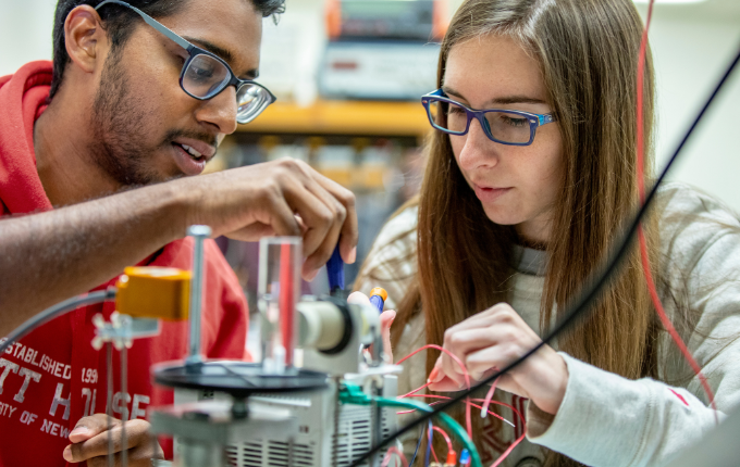 two students work on a machine