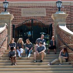 Group of students sitting outside on the steps of the Alumni Center