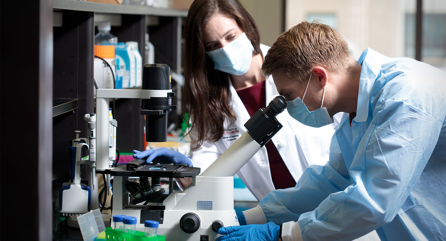 Researchers looking through a microscope. 