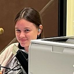 a woman working at a microscope smiling