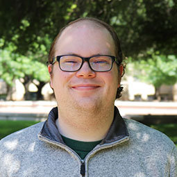 man with dark glasses on smiling outside