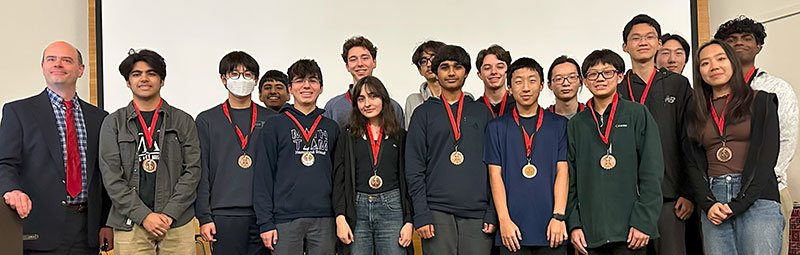 students wearing medals and holding a trophy at 2025 Math Contest Awards