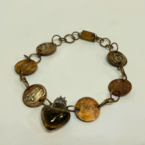 A mixed metal bracelet by Brooke Zavistaski. Each pendant represents a religious icon, historical figure, or community who has been a victim of religious violence.