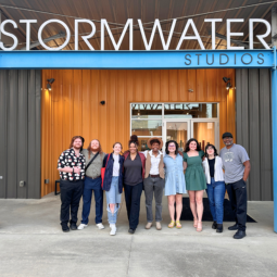A group of nine students standing in front of Stormwater Studios.