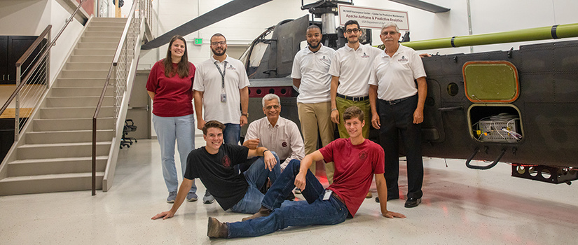 Abdel Bayoumi takes a picture with his team in front of a helicopter.