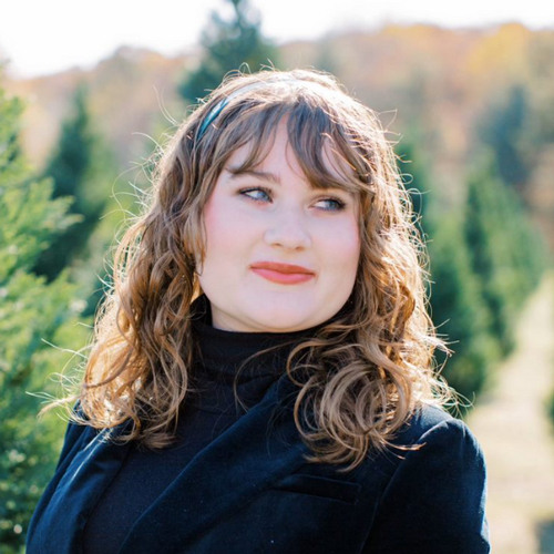 Young woman wearing a black turtleneck and black blazer.