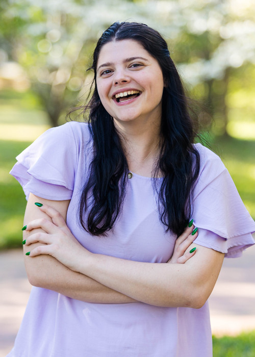 Young smiling woman with dark hair wearing a lavender blouse.