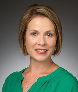 woman with short blond hair wearing a green shirt.