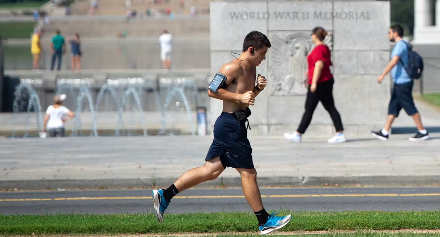 A young male jogs for exercise outdoors on a hot day.