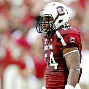 man in garnet football jersey and white helmet standing straight up