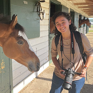 Evelyn Padilla holds camera near horse at Carolina Cup