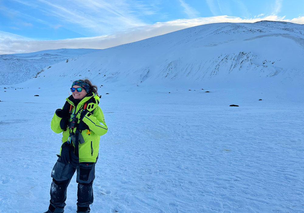 Brandi Revels in Antarctica with a snowy mountain in the background.
