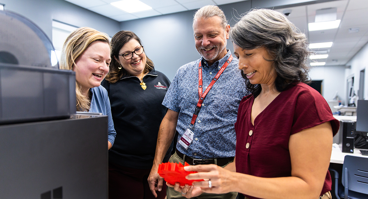 Stephanie Schaller holds a CardioEducator model as her three collaborators look on.