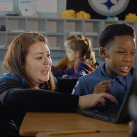 A teacher helps a student in class.